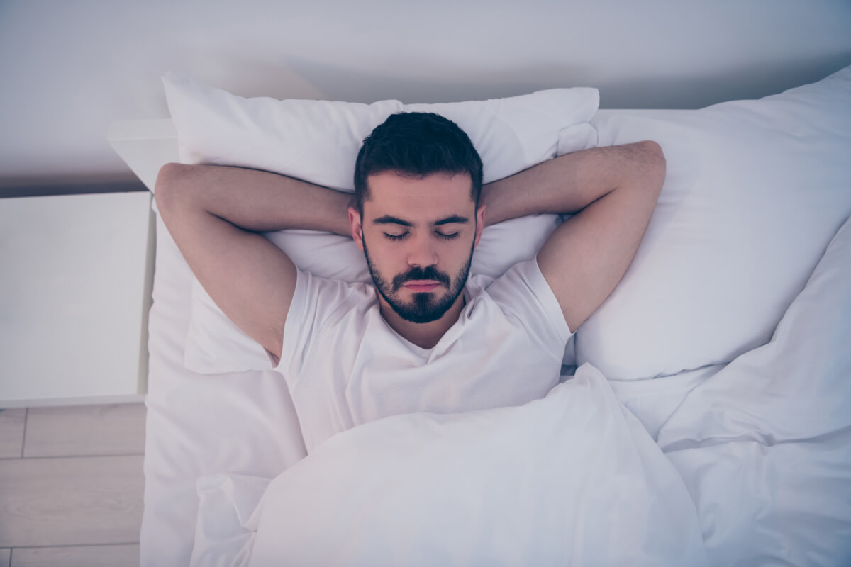 close up top high angle view portrait his he nice attractive brunette guy lying white bed resting sleeping peacefully night late evening home hotel room flat indoors