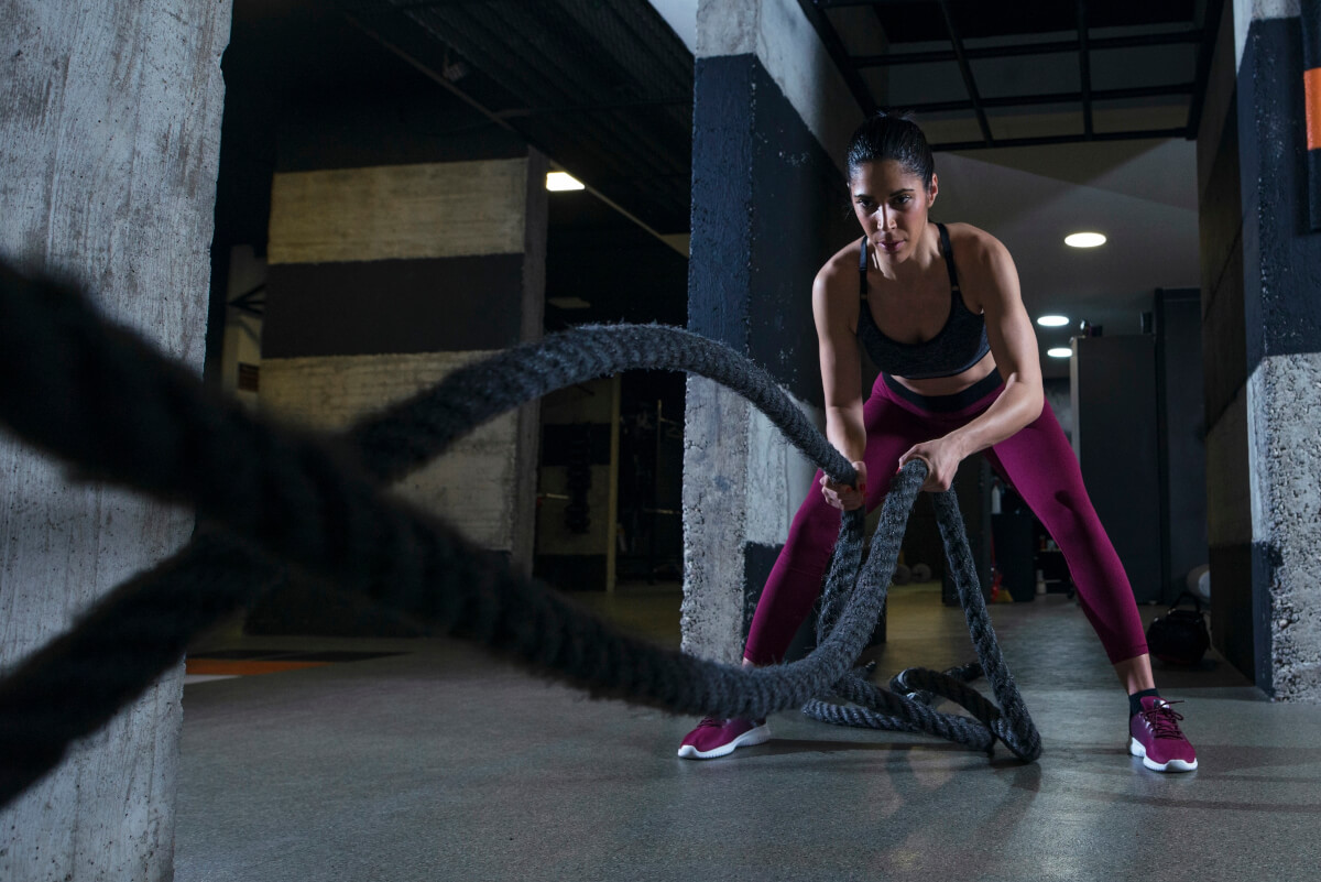 fitness woman working out with battle ropes gym