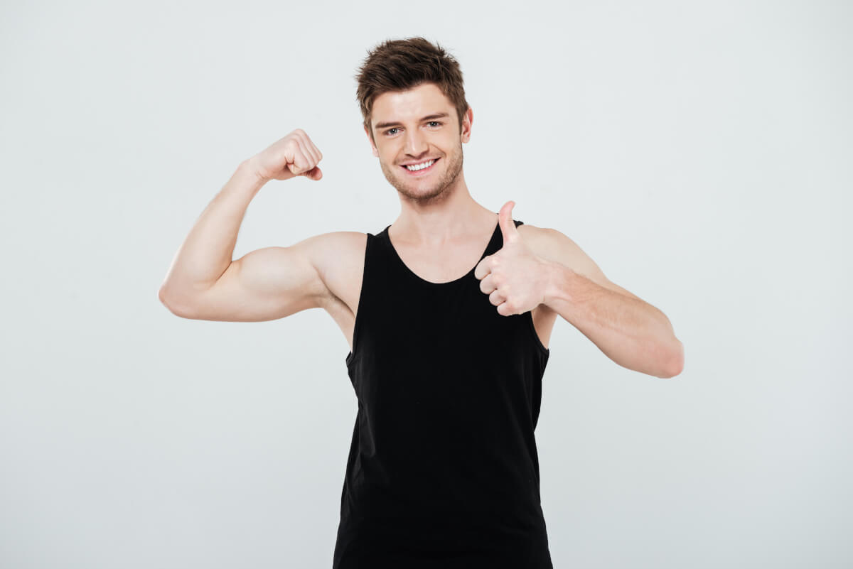 smiling young sportsman flexing biceps showing thumbs up gesture