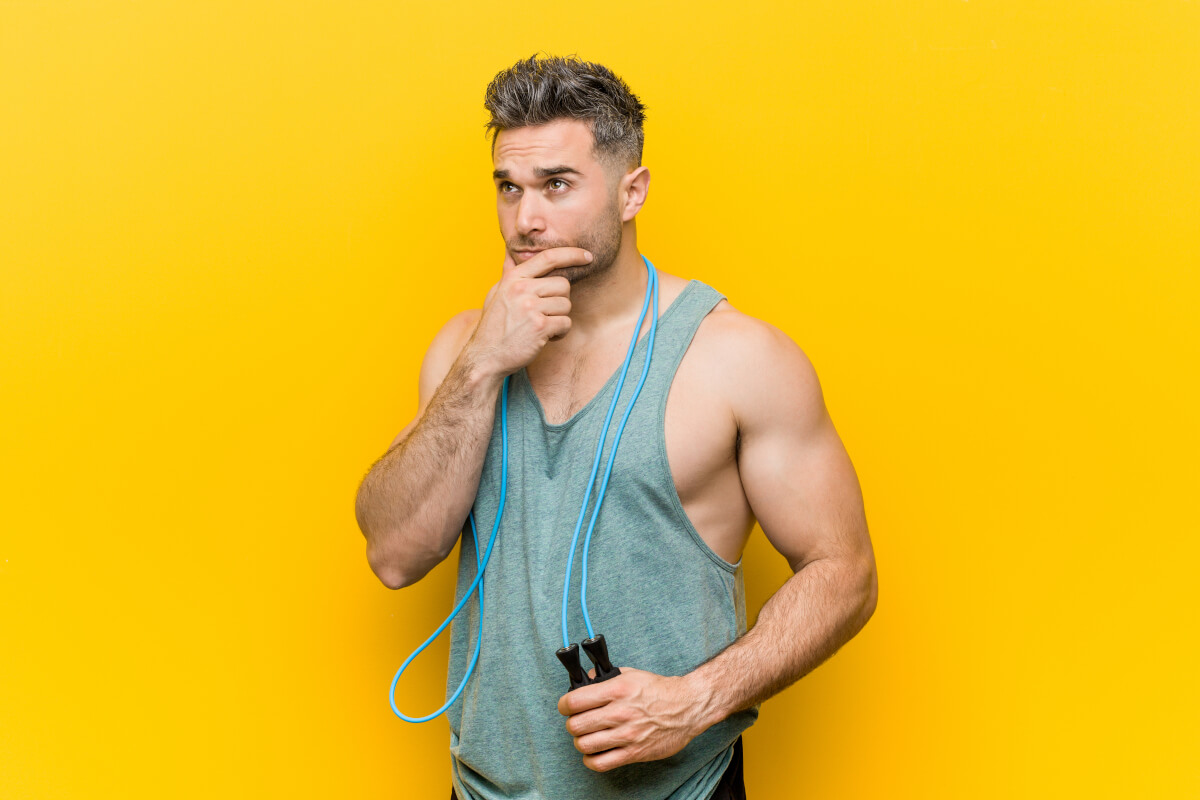 caucasian man holding jump rope looking sideways with doubtful skeptical