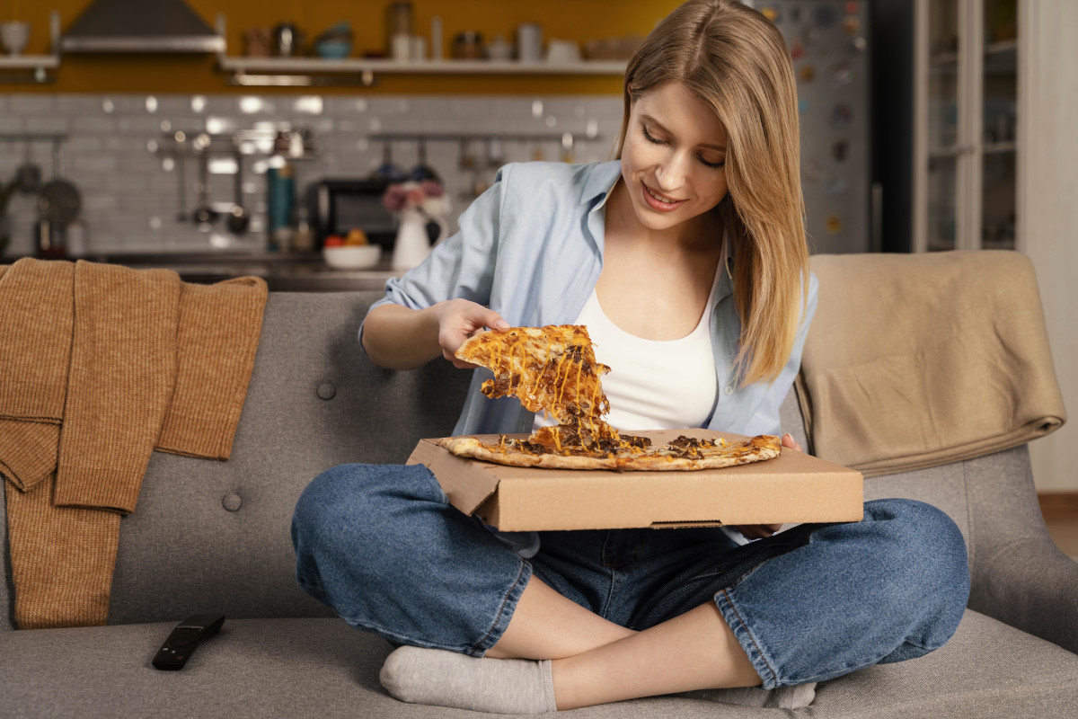 woman eating pizza while watching tv