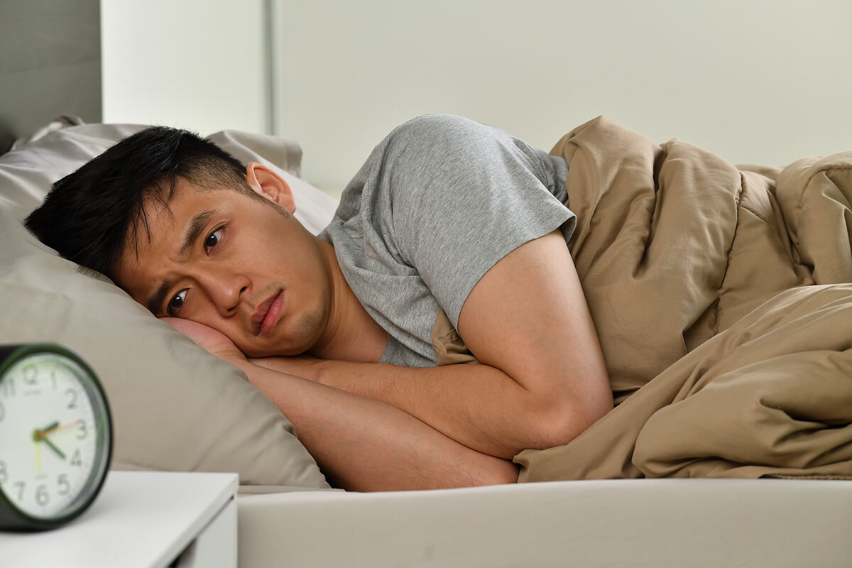 depressed young asian man lying bed cannot sleep from insomnia